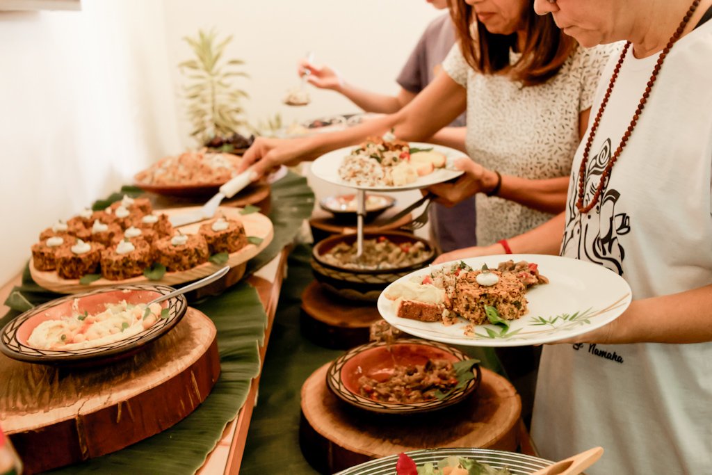 Mesa farta de celebração com pratos vegetais e convidados se servindo